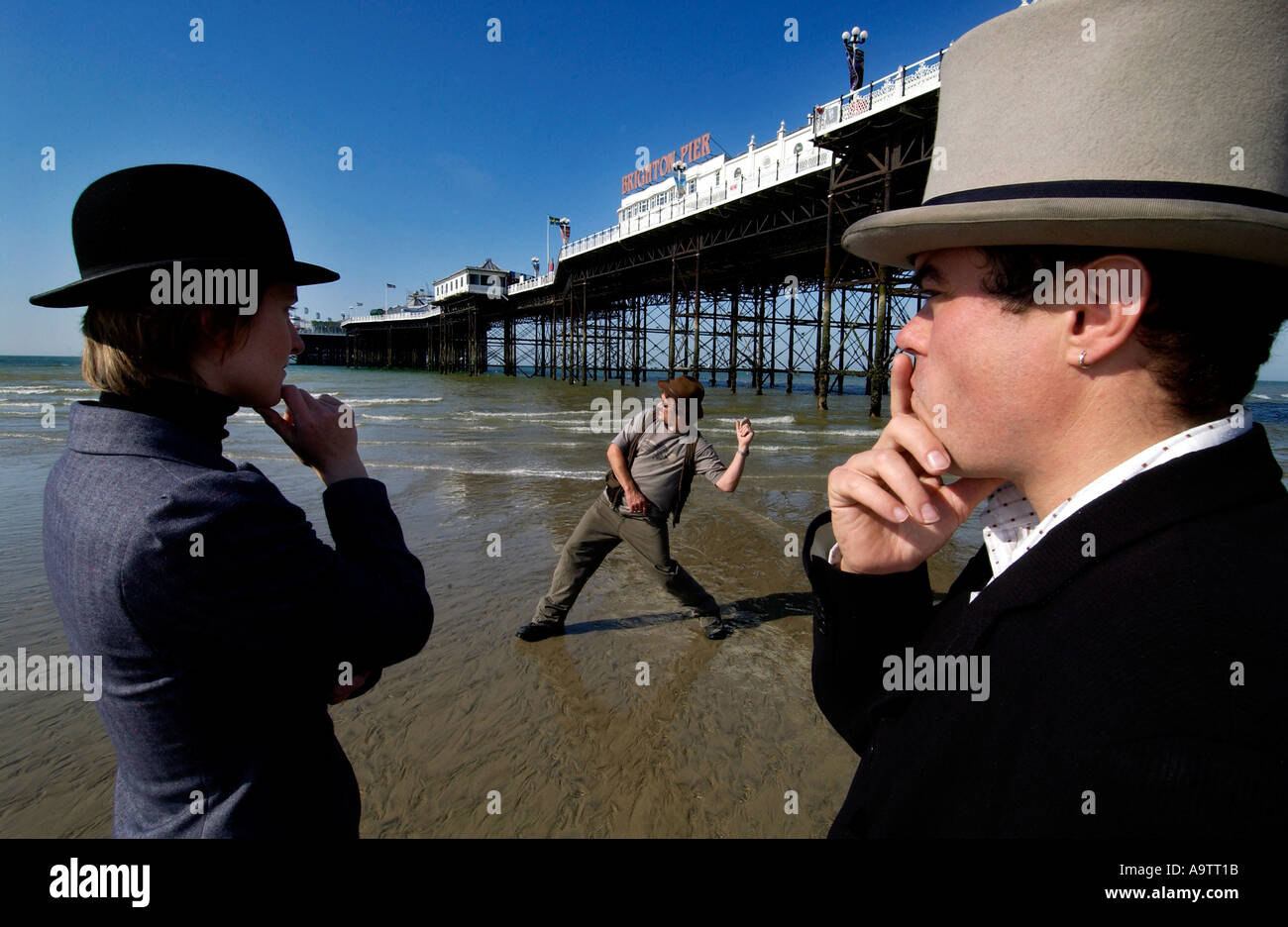 Stone skimming competition on Brighton Beach. A contender lobs a stone, watched by two judges, one in a bowler, one in a top hat Stock Photo