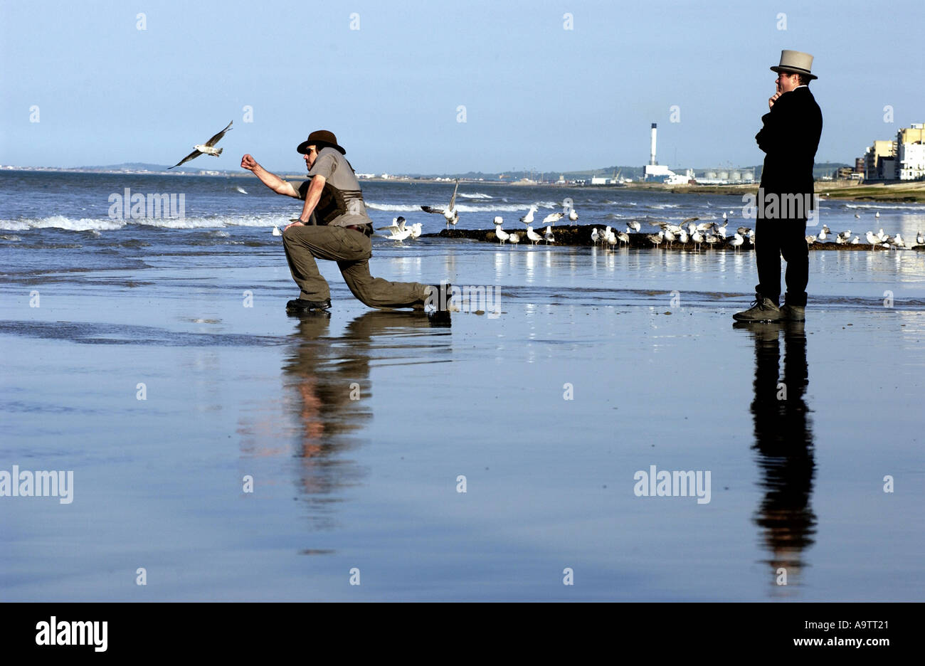 Stone skimming competition on Brighton Beach. A contender lobs a stone, watched by a judge. Stock Photo