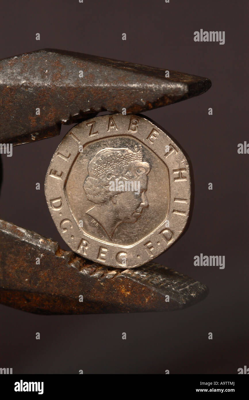 British 20p money coin in grip squeeze of pliers financial pressure concept Stock Photo