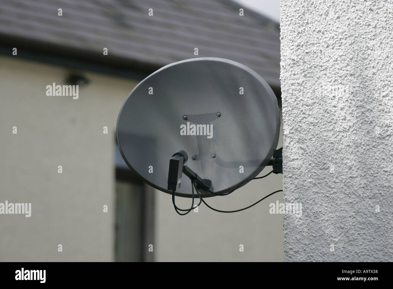 Satellite dish on side of house with pebbledash walls Stock Photo