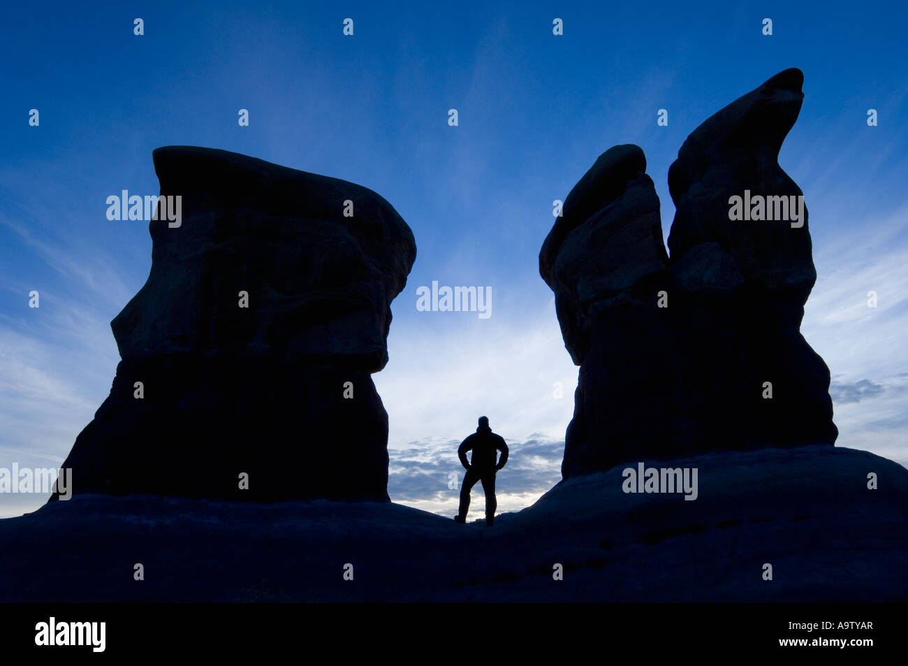 Man standing between two sandstone features in DevilÕs Garden UtahMan standing between two sandstone features in Devil's Garden Stock Photo