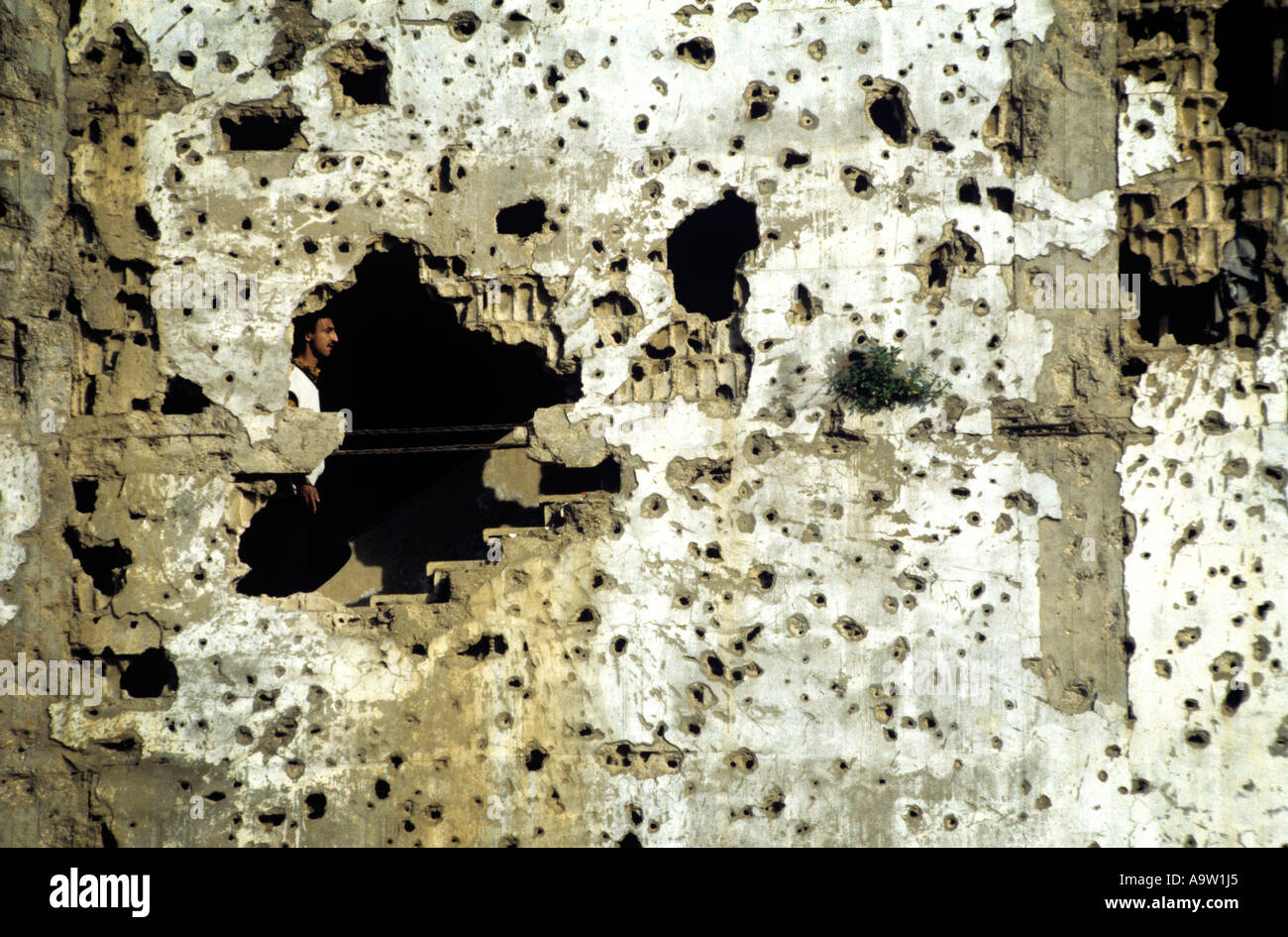 Holes made by small-arms fire reveal a man's journey up the stairs of his appartment building in the suburbs of Beirut. Stock Photo