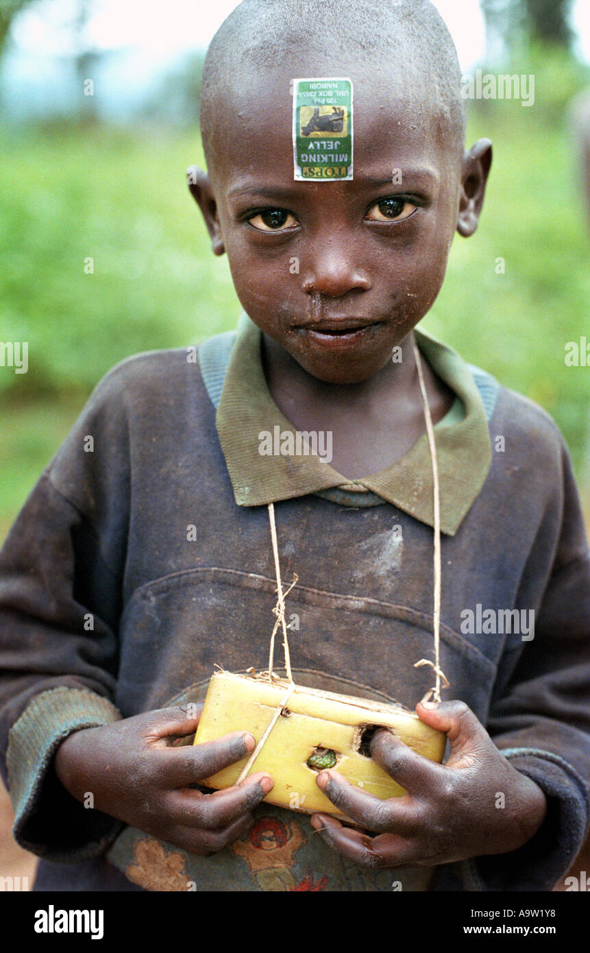 A young Rwandan boy holds a toy camera made from folded banana leaves. Stock Photo