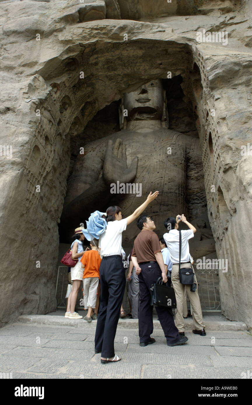 Group Of Chinese Tourists and Guide In Front Of A Giant Buddha Statue Carved Inside The Yungang Shiku Grottoes / Grotto, China Stock Photo