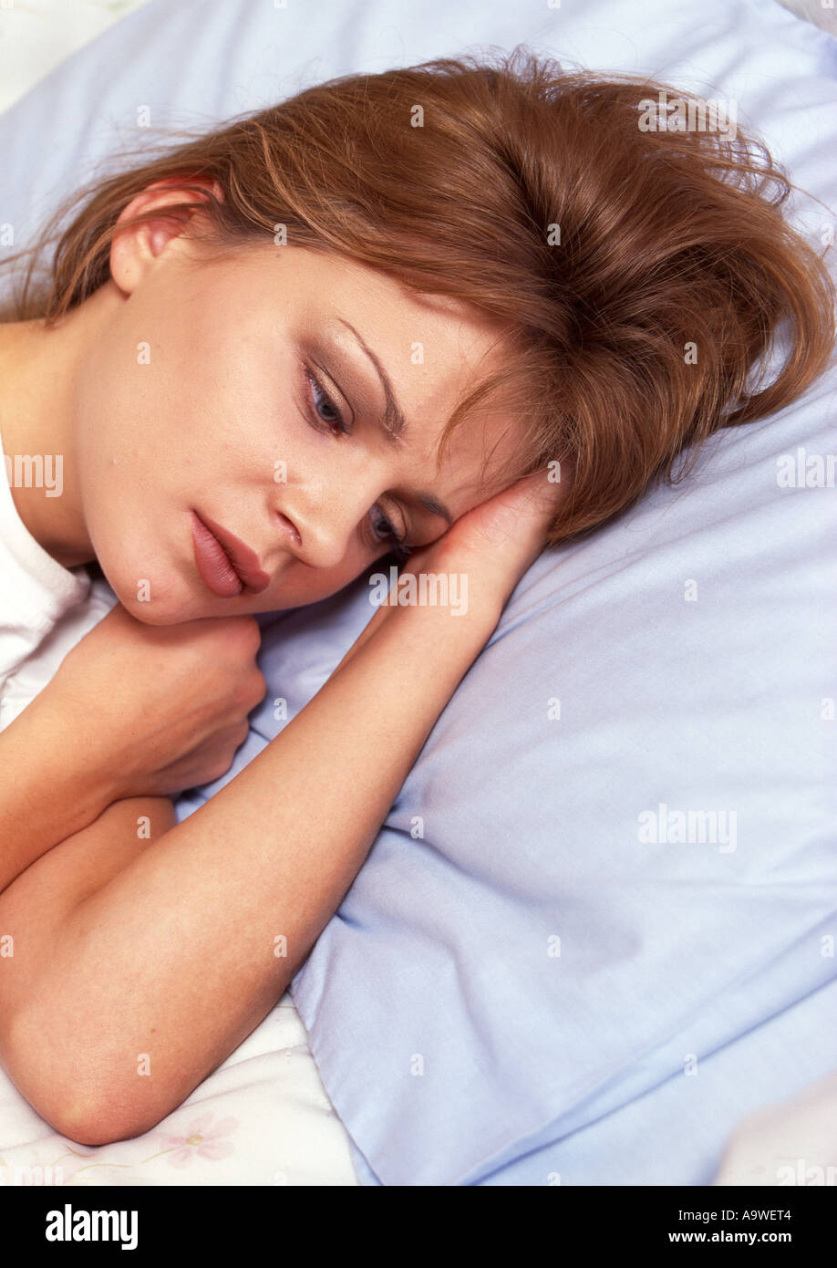 Depressed young woman lying on bed Stock Photo - Alamy
