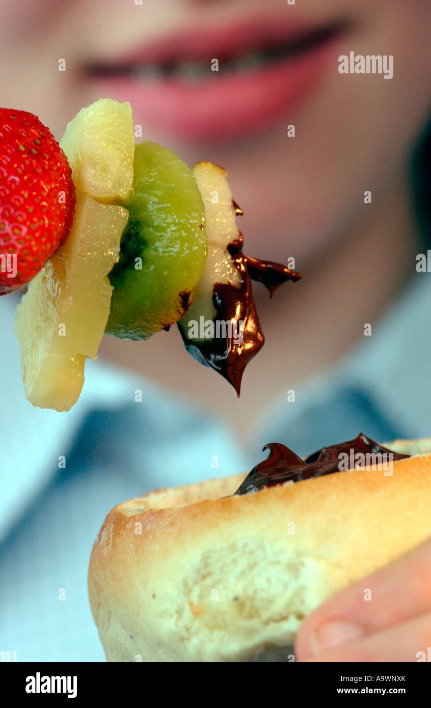 girl dipping fruit kebab into chocolate sauce Stock Photo Alamy