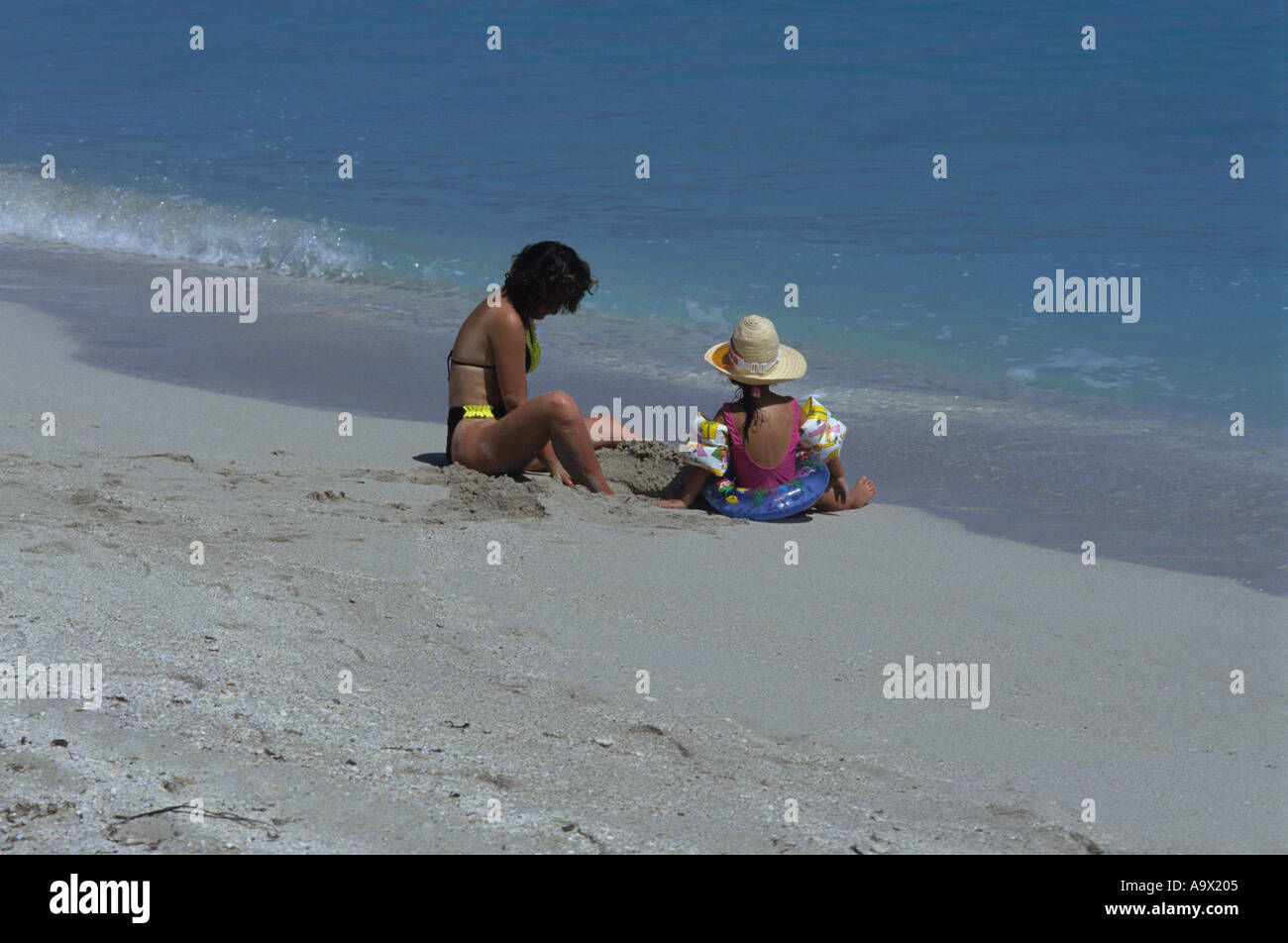 Mother and daughter on clean and empty beach daughter is wearing water wings Varadero Beach Cuba Stock Photo