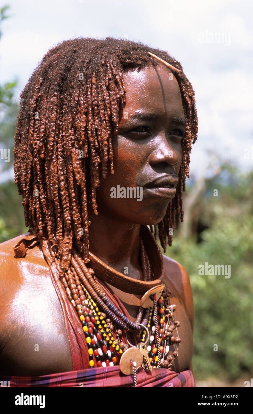 Lolgorian, Kenya. Siria Maasai Manyatta; a moran, red ochre coloured braided hair, shell and bead decorations, keys. Stock Photo