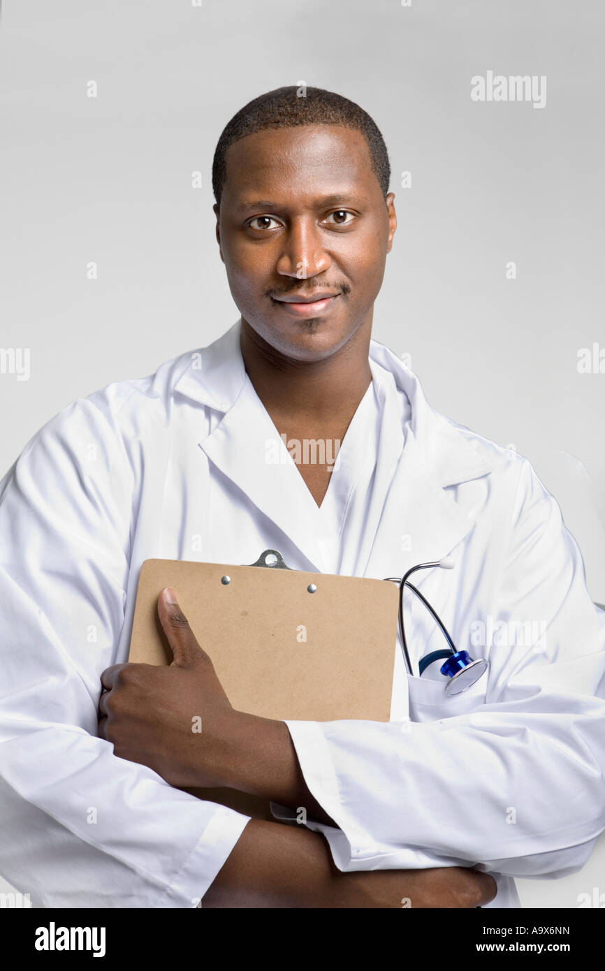 Young black doctor wearing a white coat and stethoscope holding a clipboard and smiling at the