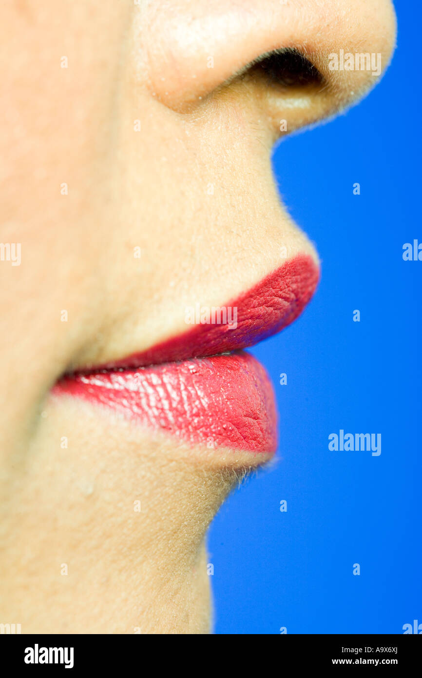 mouth and nose of a pretty woman wearing red lipstick on a blue back ground Stock Photo