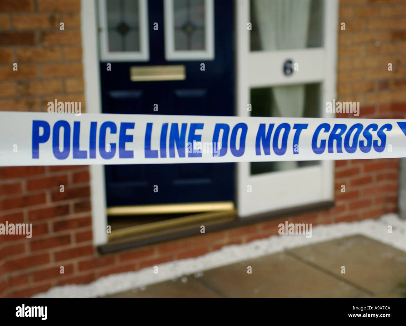 blue and white police tape cordoning off a crime scene Stock Photo