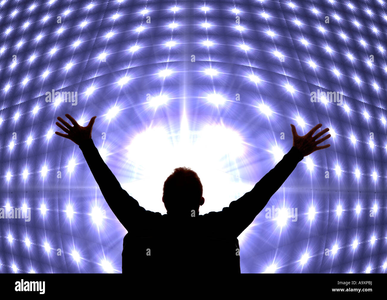 silhouette of celebrating businessman with arms outstretched in front of huge electronic TV screen Stock Photo