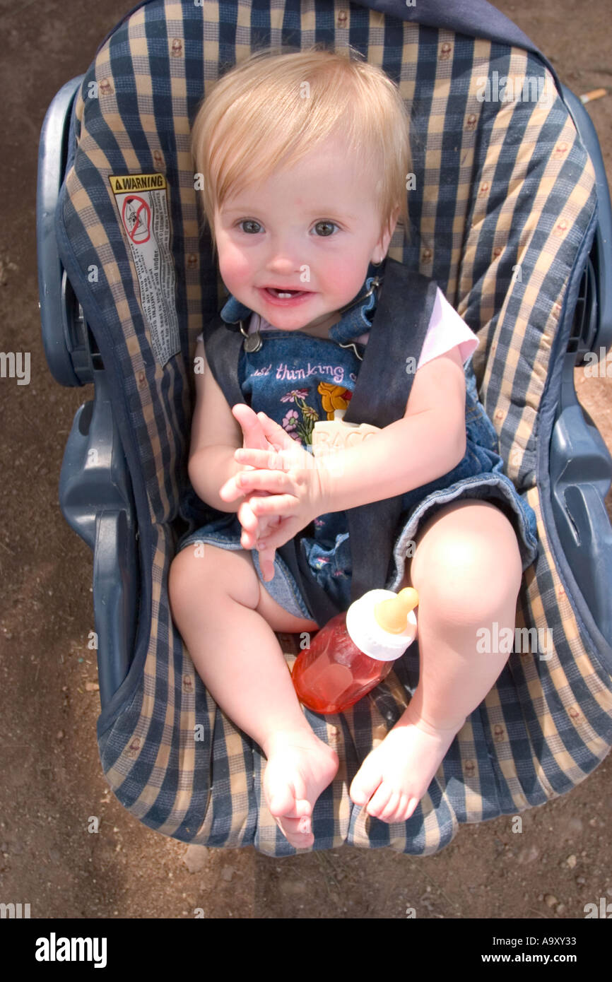Baby girl in her car seat, drinking from her bottle Stock Photo