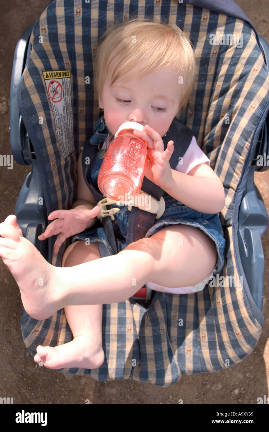 Baby girl in her car seat drinking from her bottle Stock Photo