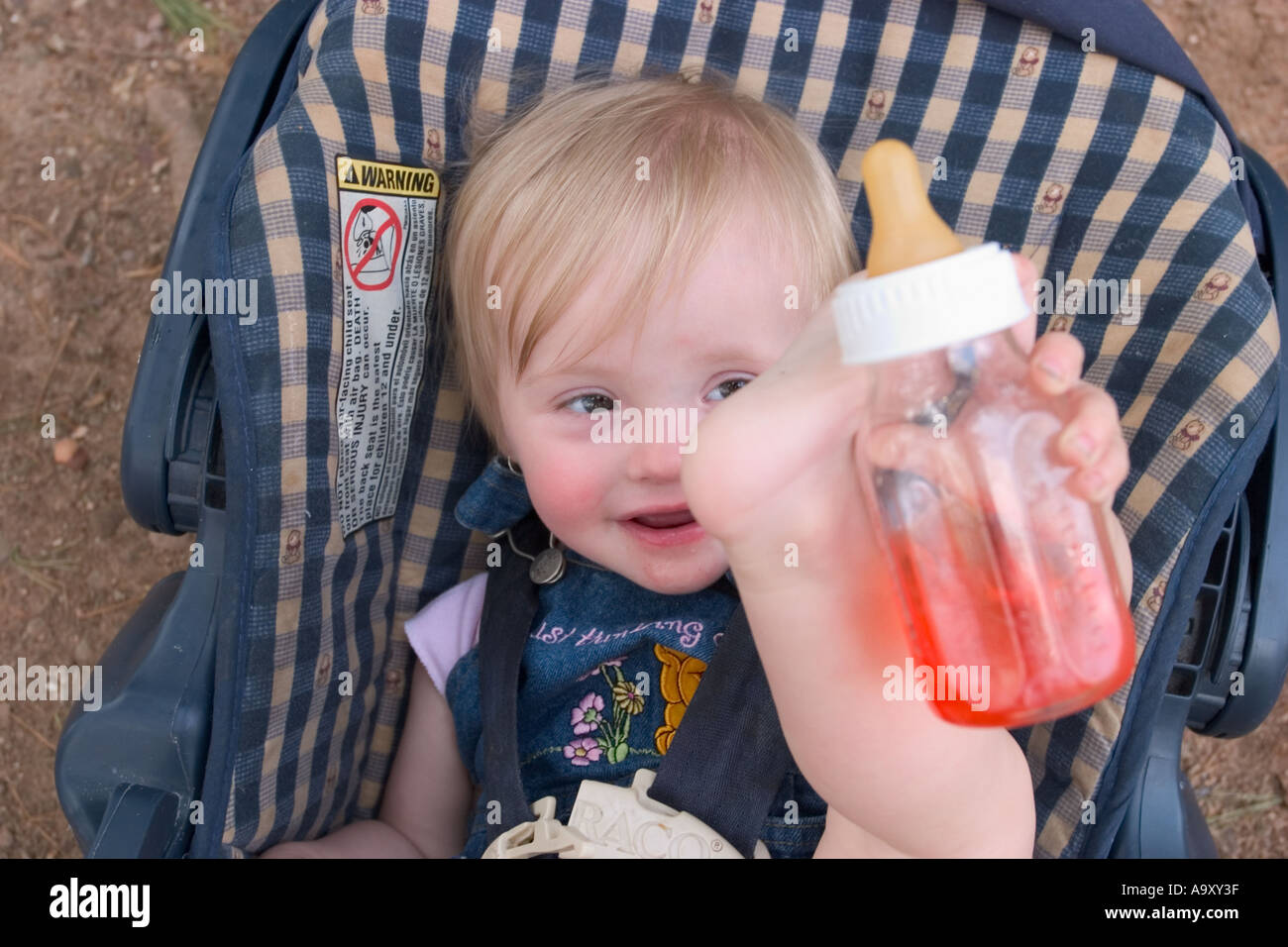 Baby girl in her car seat, drinking from her bottle Stock Photo Alamy
