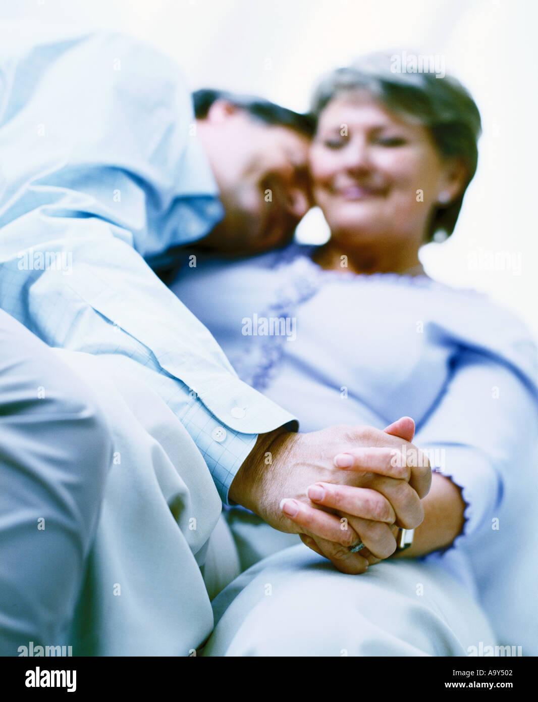 middle aged couple holding hands on sofa Stock Photo