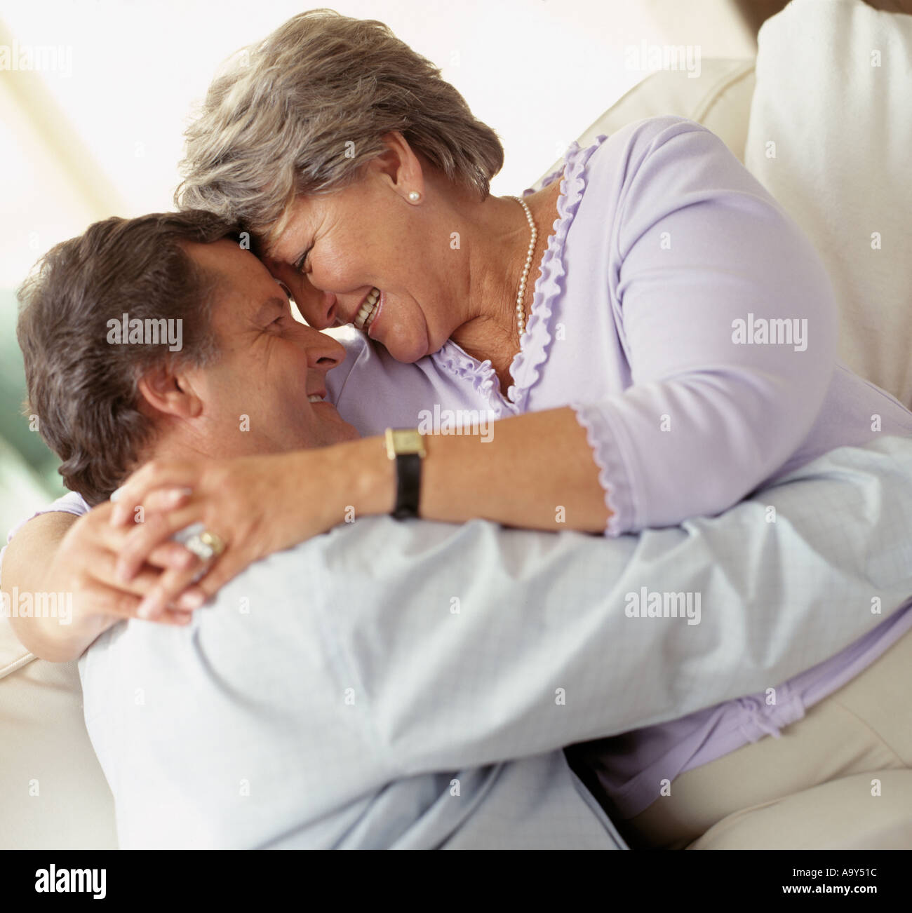 middle aged couple hugging on sofa Stock Photo