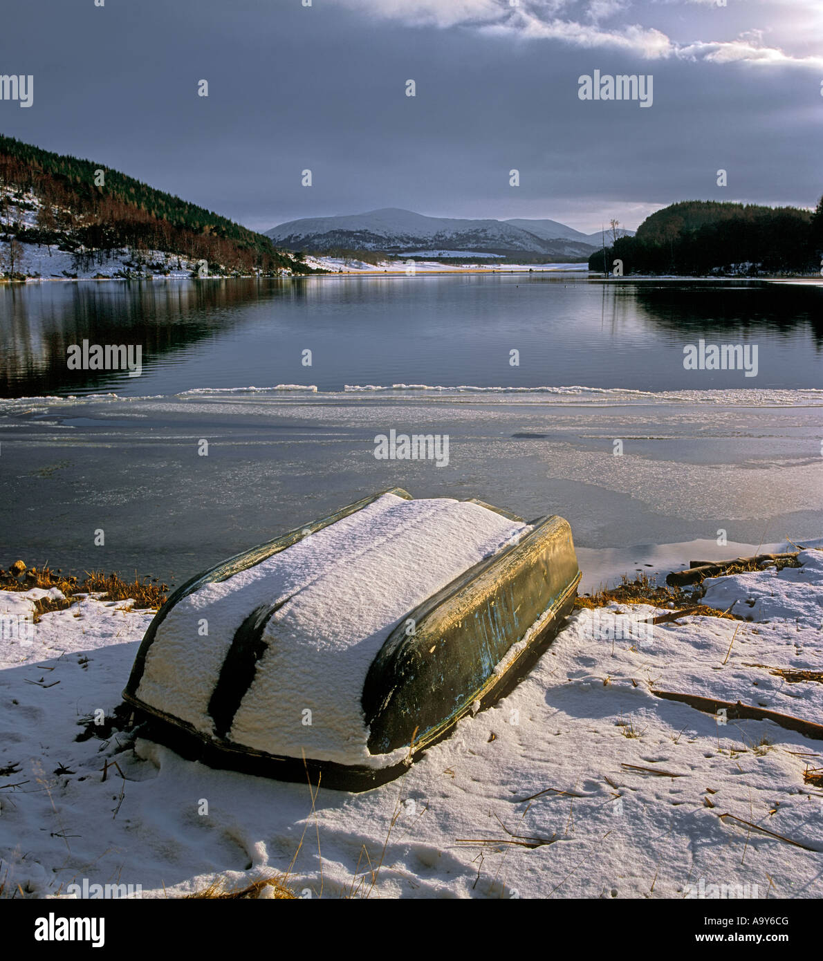 An upturned boat covered in fresh snow bides its time until next Spring at the edge of Loch Pityoulish, Cairngorm, Scotland. Stock Photo