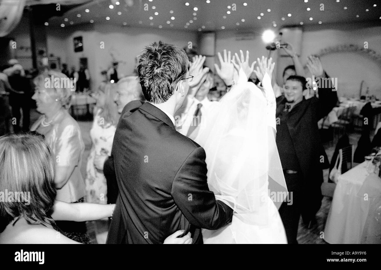Poland, Lodz, bride with groom and wedding guests dancing in party (B&W) Stock Photo
