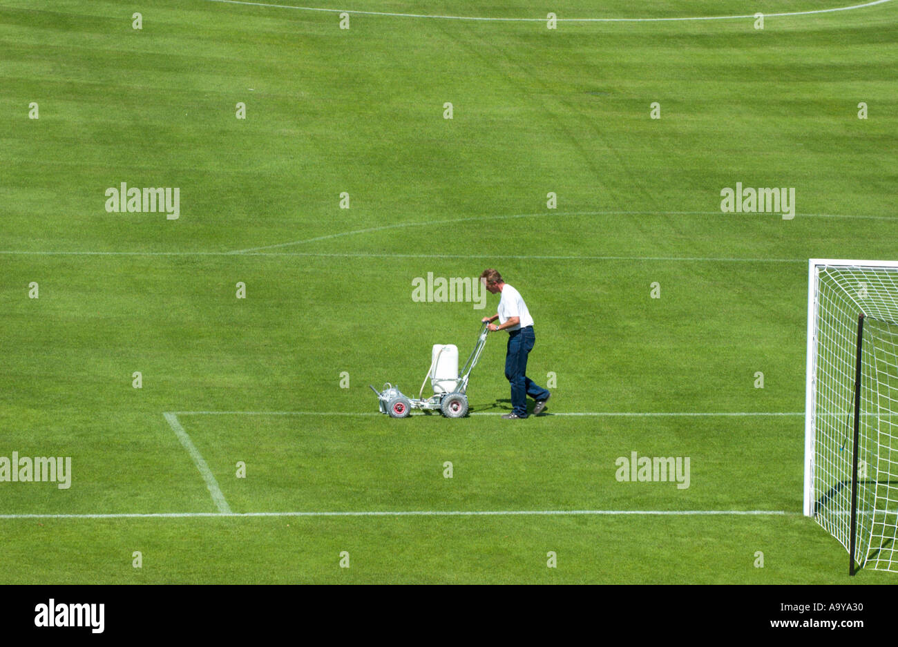 groundkeeper chalks the lines of the penalty box of a football pitch Stock Photo