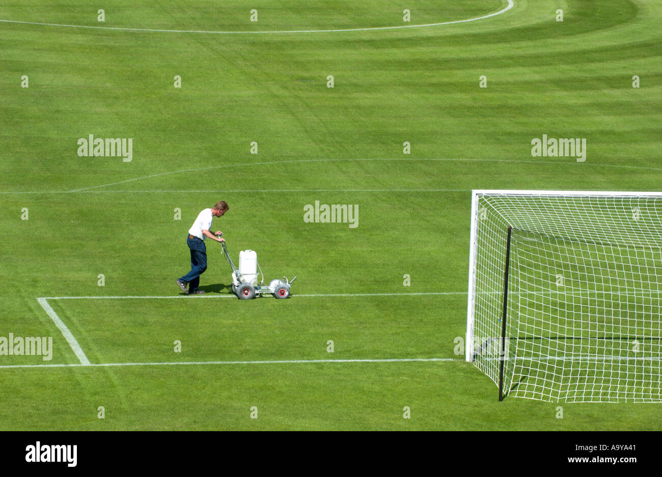 groundskeeper chalks the lines of the penalty box of a football pitch