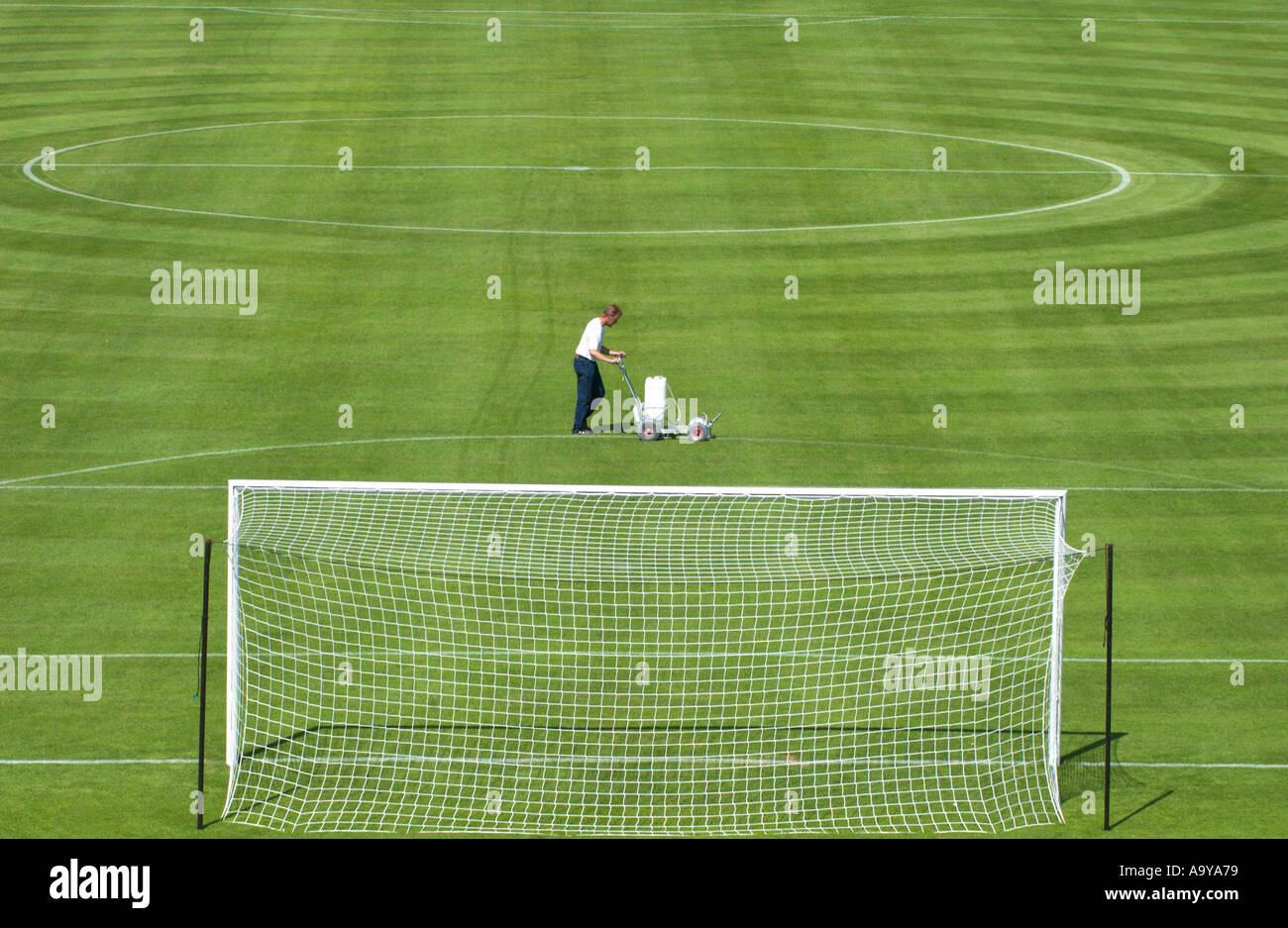 groundkeeper chalks the lines of the penalty box of a football pitch Stock Photo