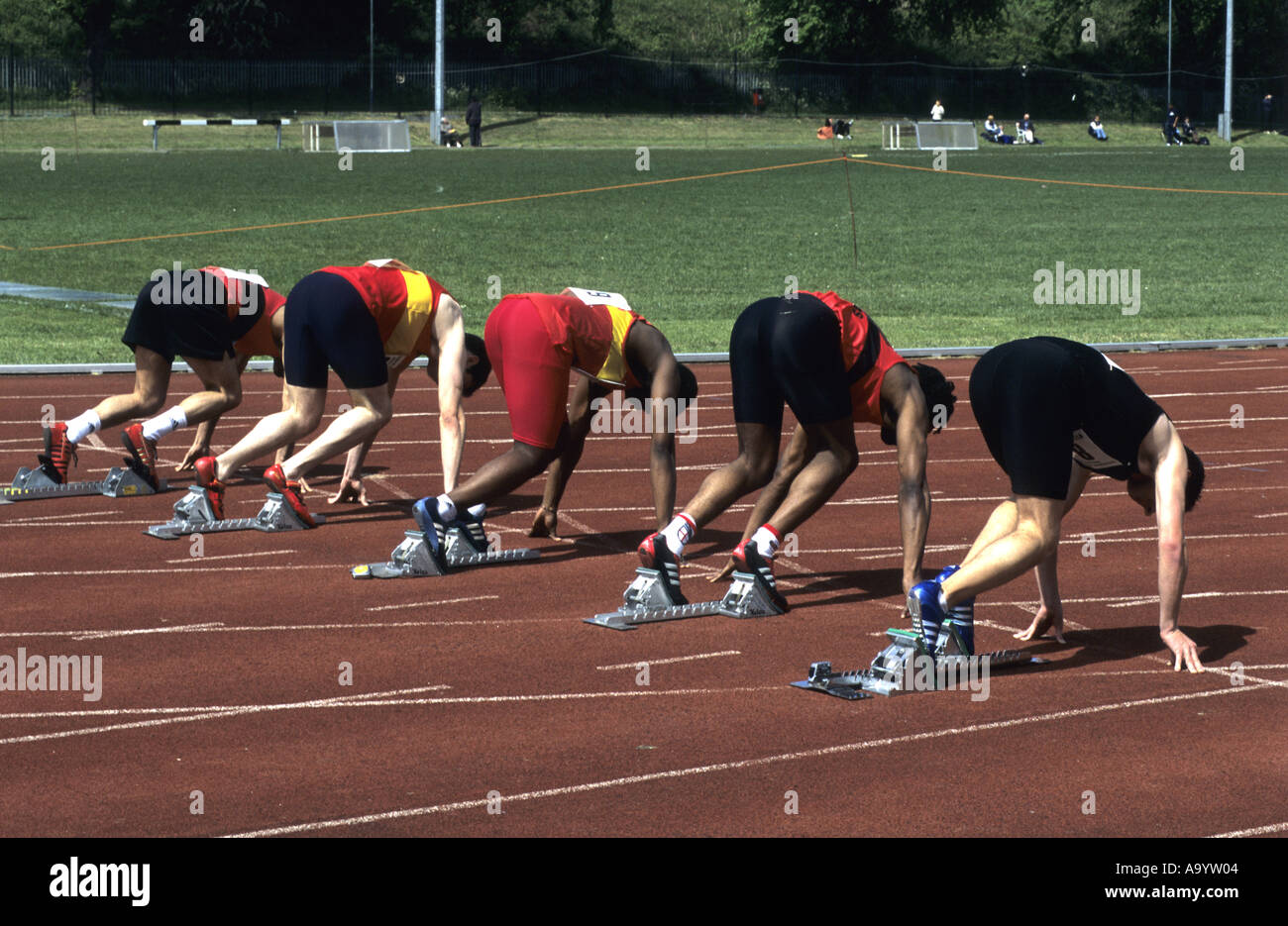 Runners in set position before 100m race on an athletics track, UK Stock Photo