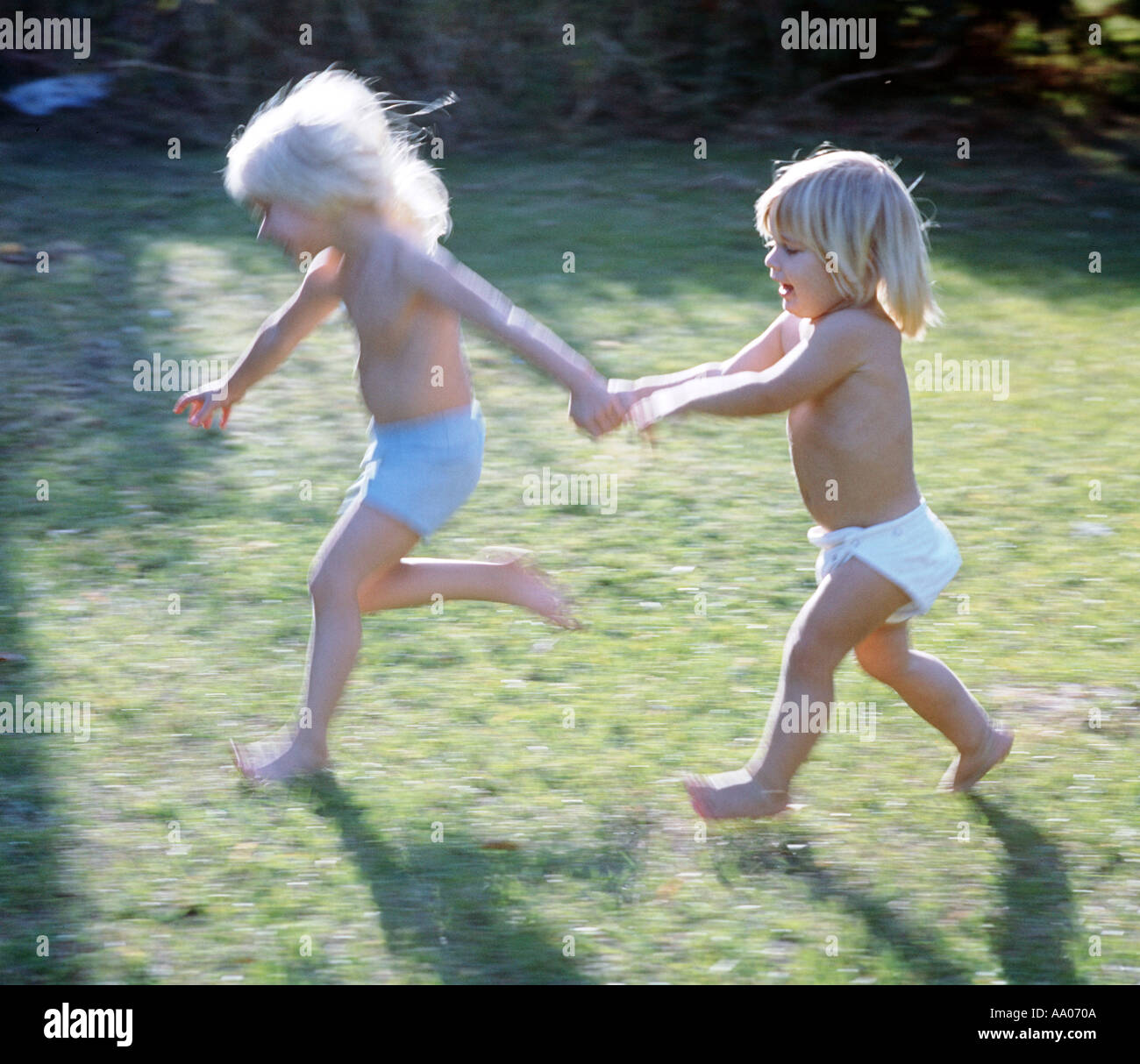 small boy and girl running in yard Stock Photo