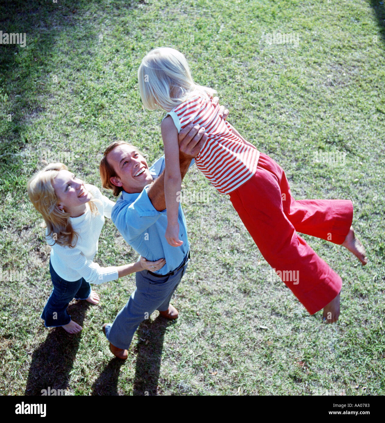 father and mother playing with young daughter outdoors Stock Photo