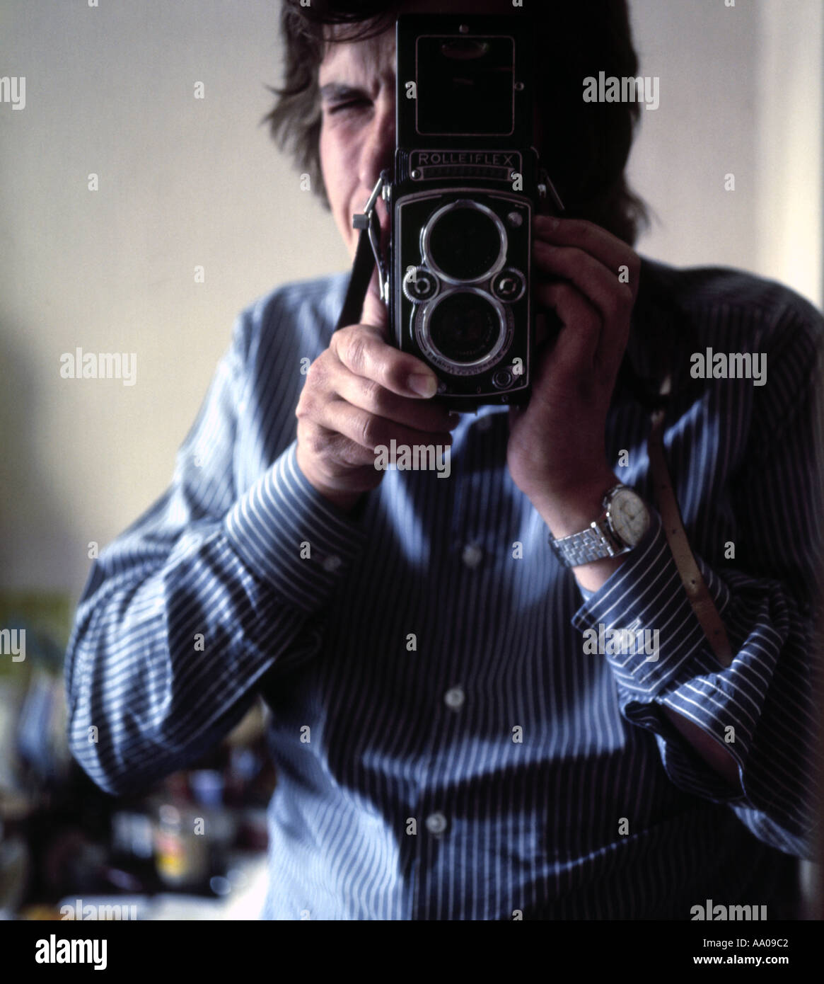Man in a striped shirt taking a photograph with a classic Rolleiflex twin lens reflex camera in 1974 Stock Photo