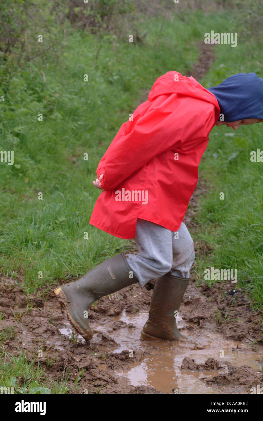 Child wearing wellington boots and jumping in a muddy puddle Stock ...