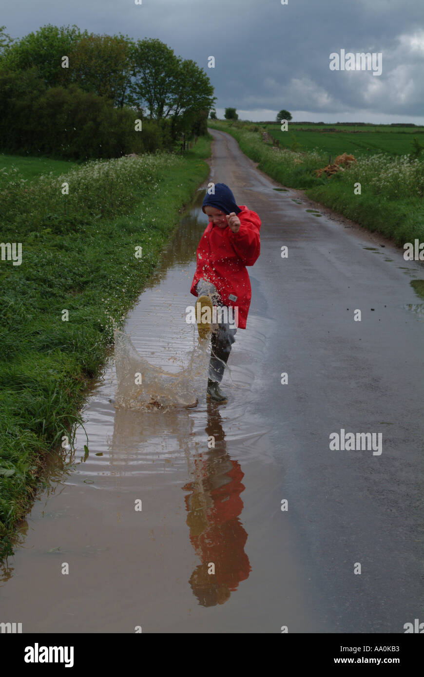 Child wearing wellington boots and jumping in a puddle Stock Photo - Alamy