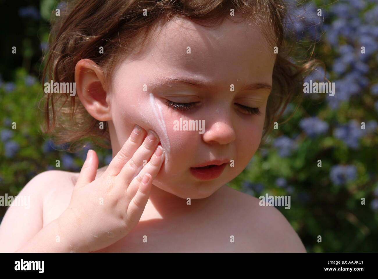 Toddler rubbing sunscreen onto her face Stock Photo Alamy