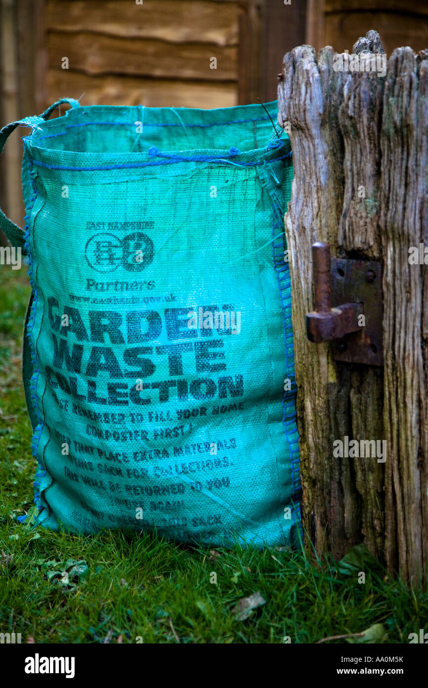 Bag of garden waste awaiting collection next to old gate post Stock Photo