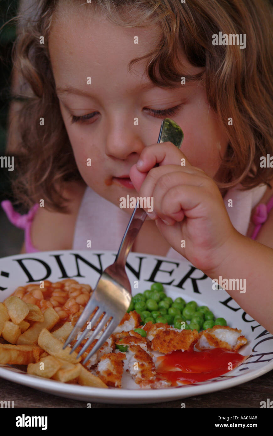 Girl eating chips fish fingers peas and beans Stock Photo Alamy