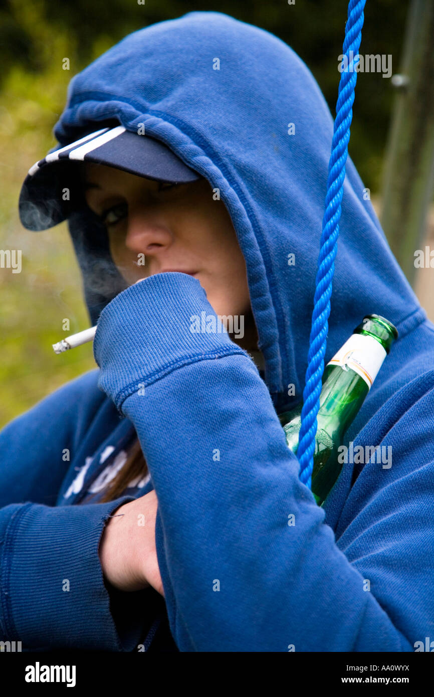 Young female smoking wearing a baseball cap and hooded sweatshirt Stock Photo