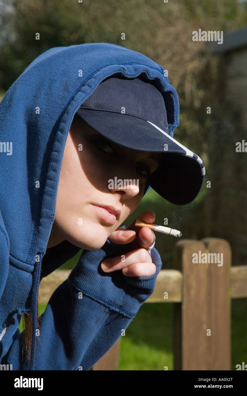 Young female smoking wearing a baseball cap and hooded sweatshirt Stock Photo