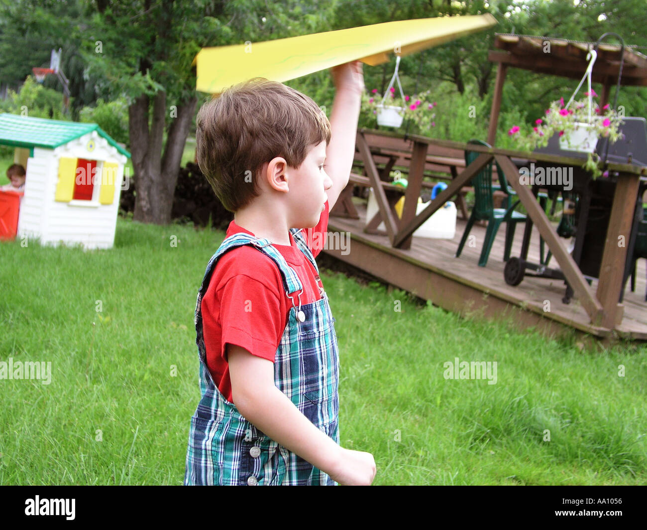BOY WITH PAPER AIRPLANE flying in backyard Little brother in the distance Photographed in Pennsylvania Stock Photo
