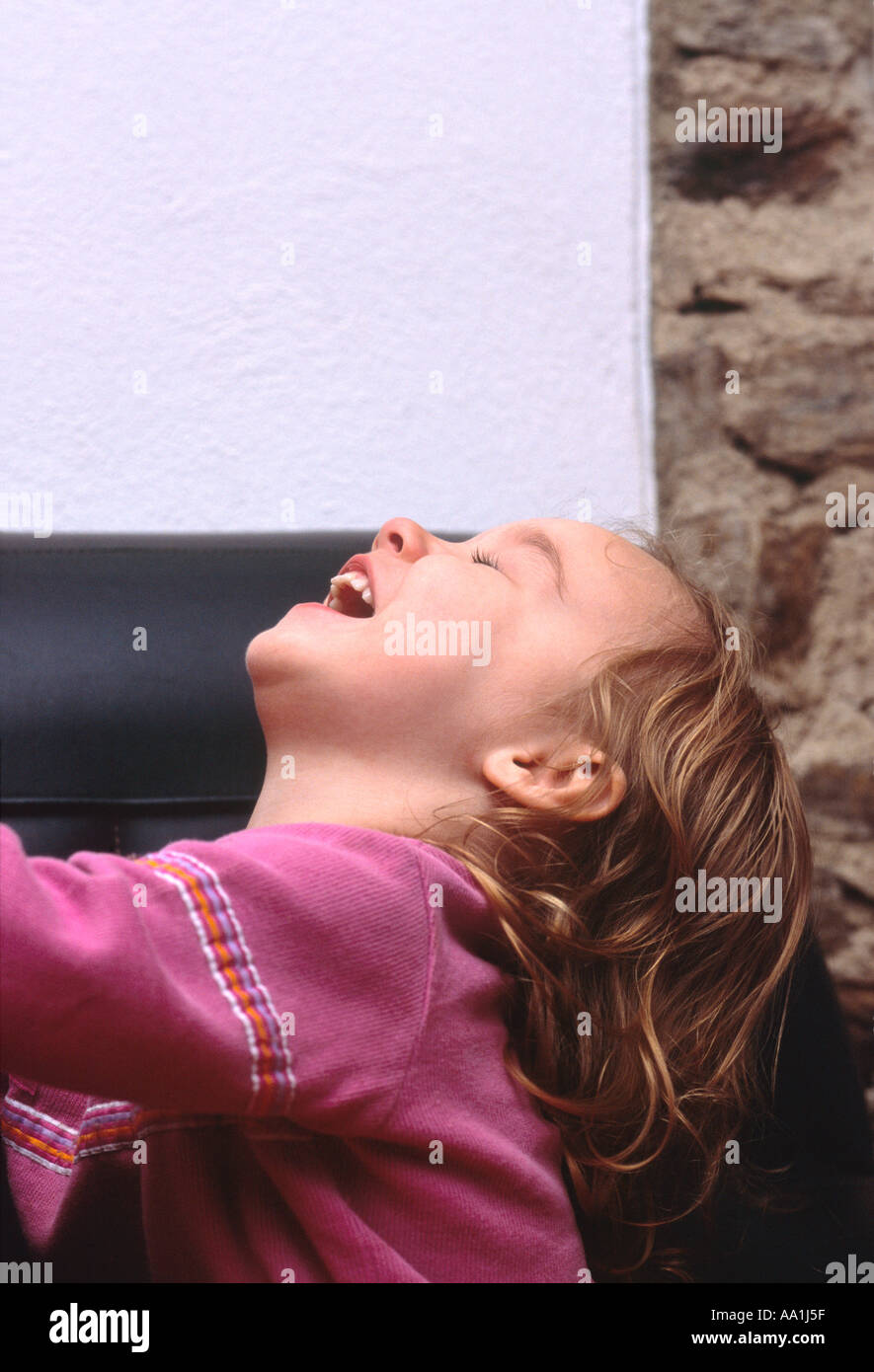 A young girl happily throwing her head back and laughing Stock Photo