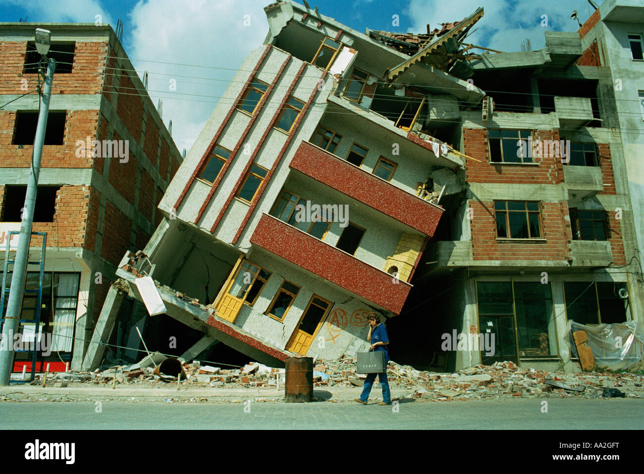 Woman on her mobile phone passing the remains of a building destroyed ...