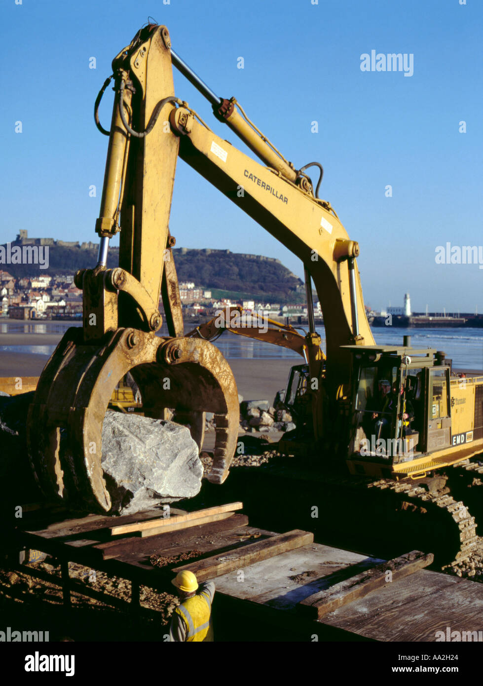 Hydraulic machine lifting a boulder off a lorry, Scarborough, North