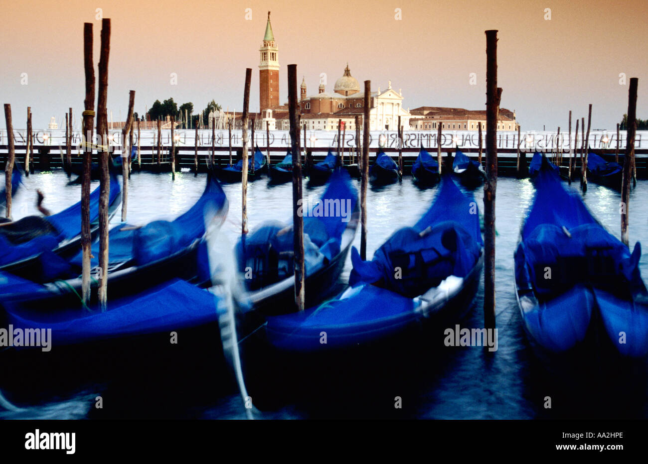 Italy, Venice, blurred gondolas and San Giorgio Maggiore island and church at dusk, blue gondolas moored Stock Photo