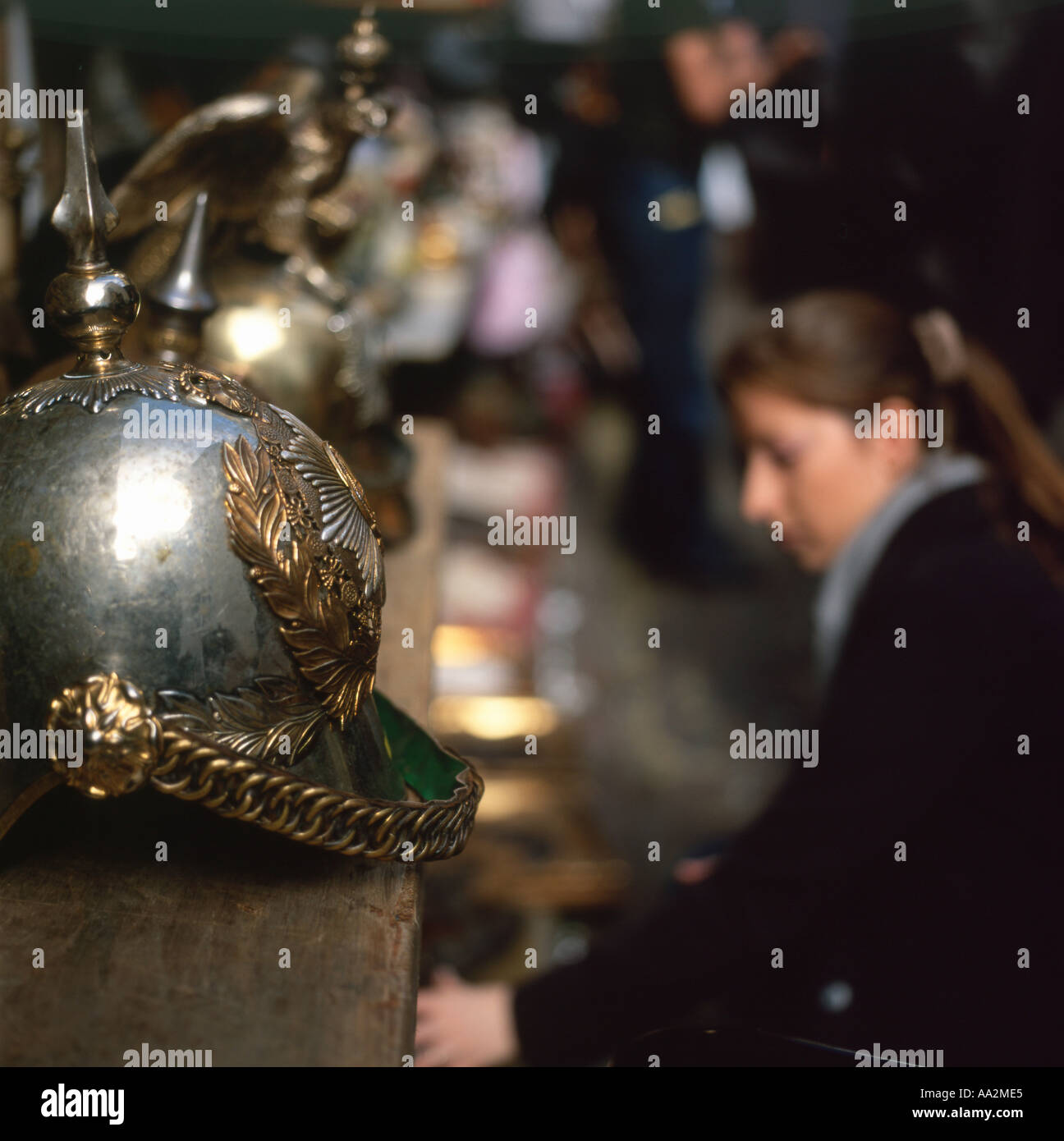 A  woman crouching near a metal Queens horse guard's helmet on display Portobello Road Market London England UK Stock Photo