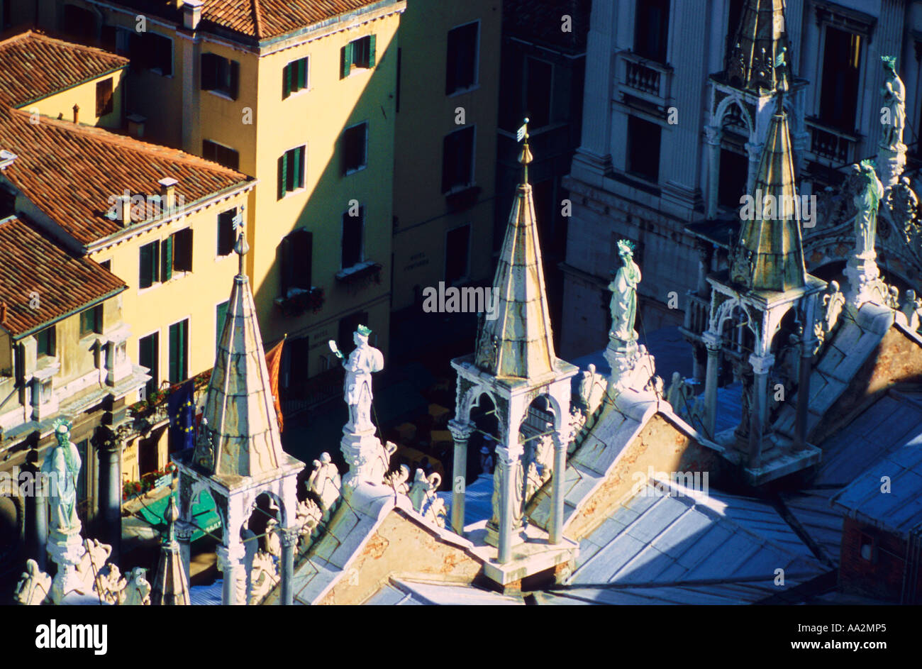 Italy, Venice, Basilica di San Marco Saint Mark Basilique with stone carvings on rooftop overlooking sunlit yellow buildings, el Stock Photo