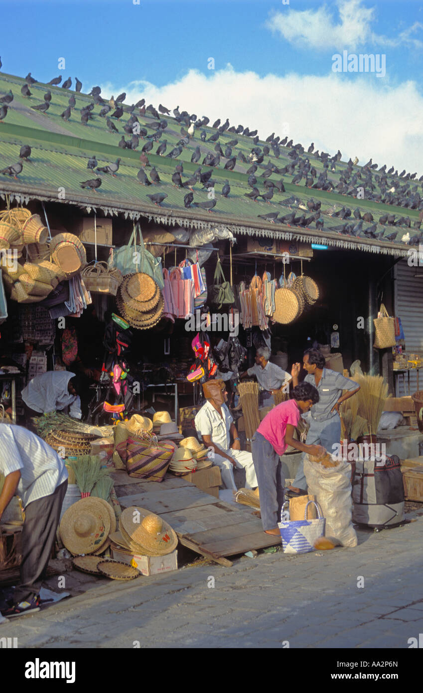 Straw and wicker hats, baskets, man talking to man wearing leather headgear, stallholders performing various activities , market Port Louis, Mauritius Stock Photo