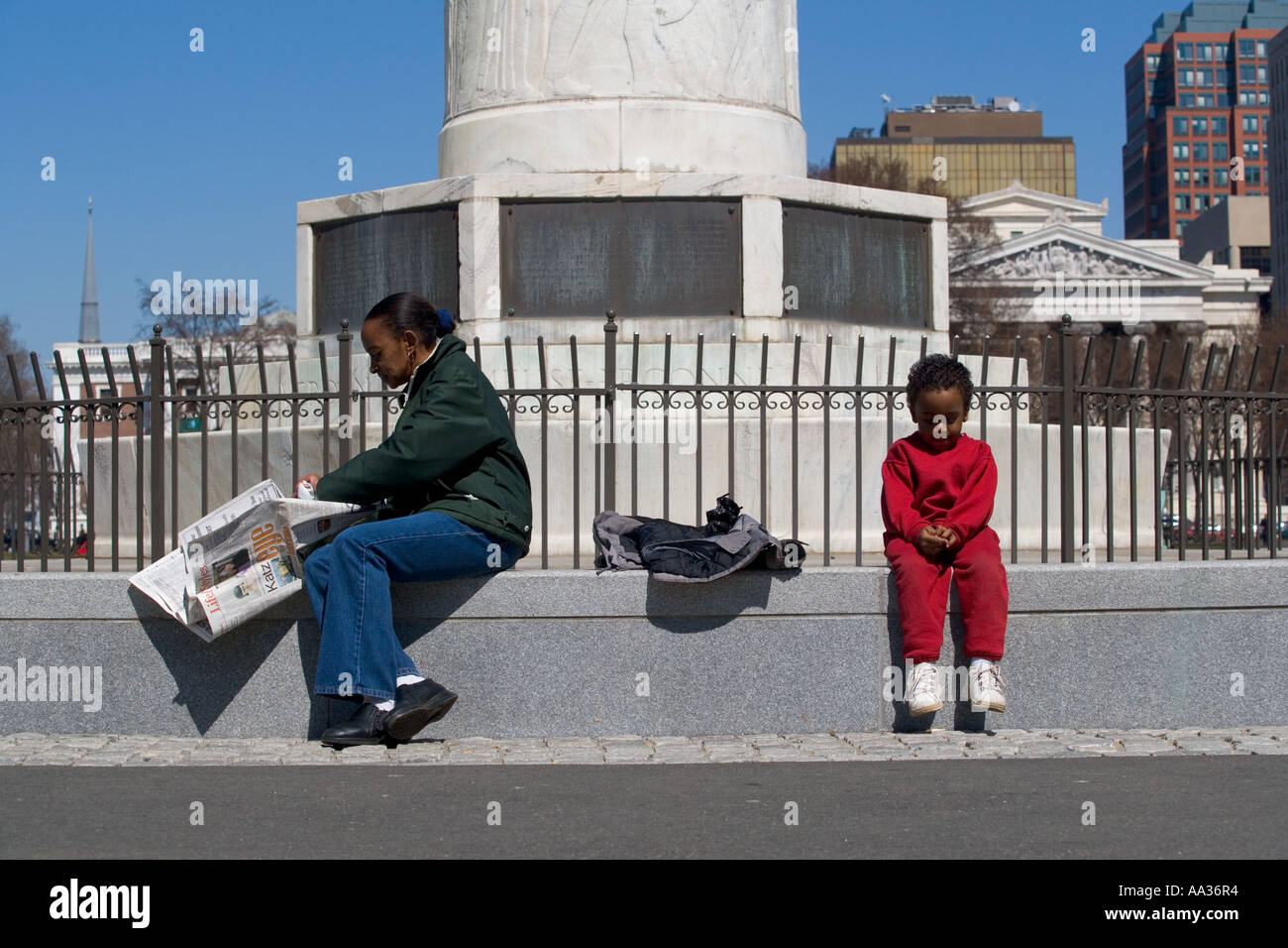 A mother reads the newspaper white a young boy relaxes Stock Photo