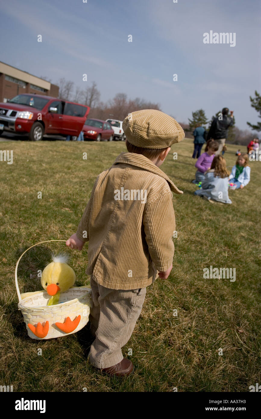 Easter Egg Hunt, small boy with irish hat and courdoroy jacket and basket looking for candy and treats Stock Photo