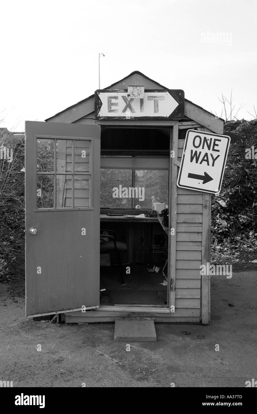 small guard shack at a junk yard public trash facility exit sign and one way traffic arrow Stock Photo