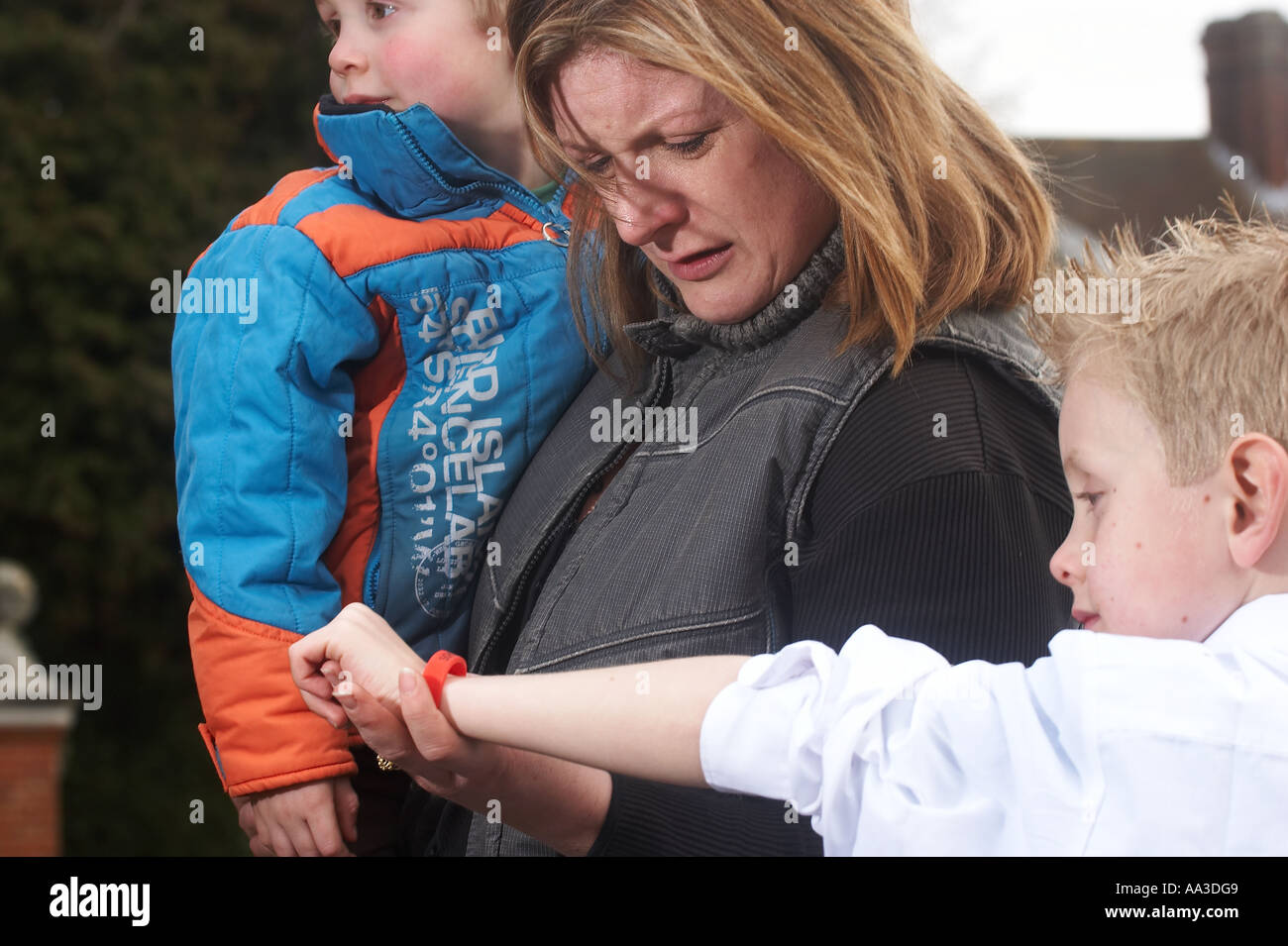 Small child lost in a crowd with a lady looking at his wristband to identify him Stock Photo