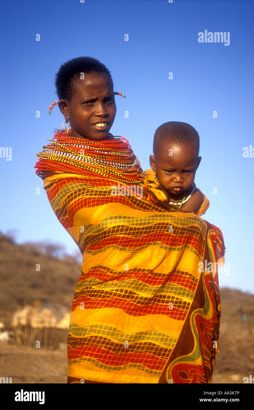 Young Samburu woman carrying her baby on her hip wrapped in colourful cotton Northern Kenya East Africa Stock Photo